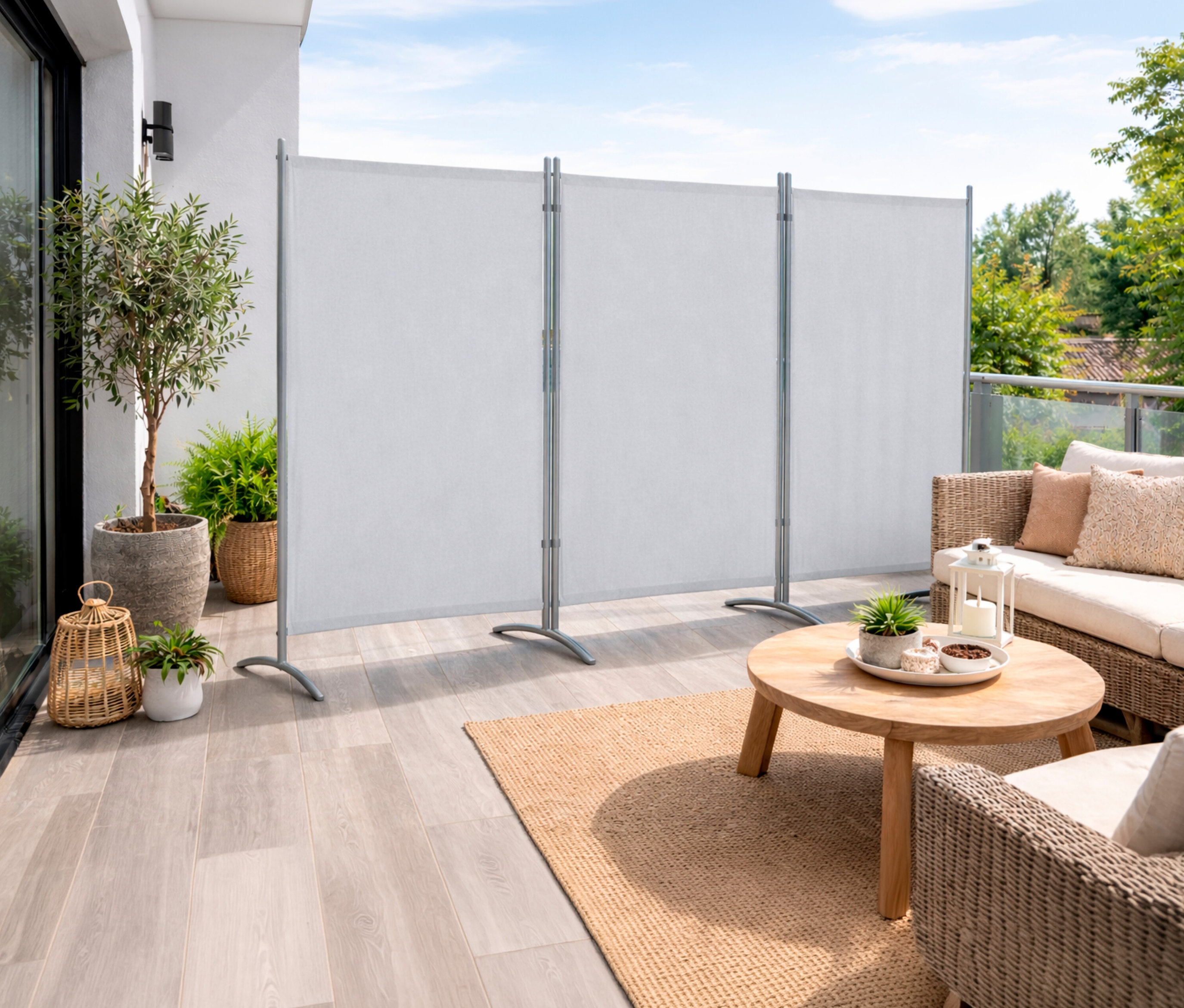 Auf einer Terrasse steht eine helle Leco 3-teilige Stellwand neben einem Rattansofa und einem Tisch.