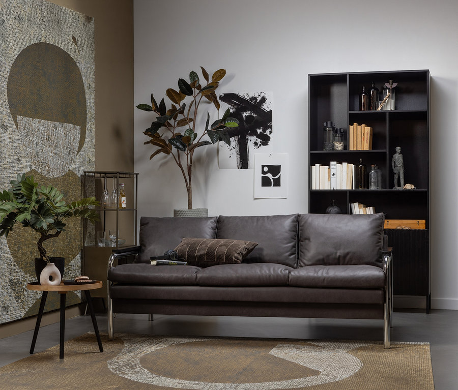 Wohnzimmer mit braunem Sofa, schwarzem Regal und Woood Beistelltisch »Mesa M« aus naturfarbenem Holz neben einer Zimmerpflanze.