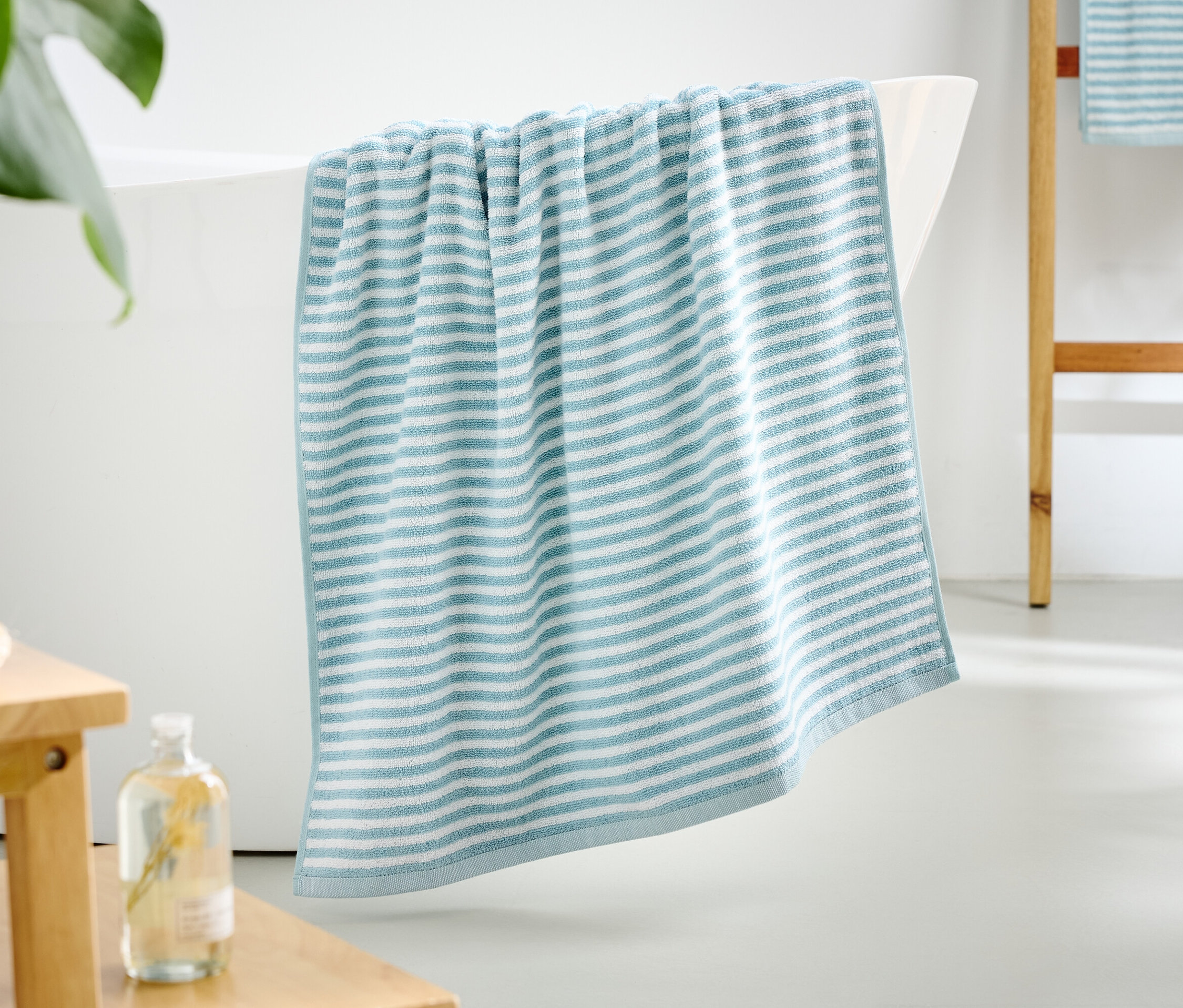 Ein blau-weiß gestreiftes Handtuch hängt über dem Rand einer Badewanne.