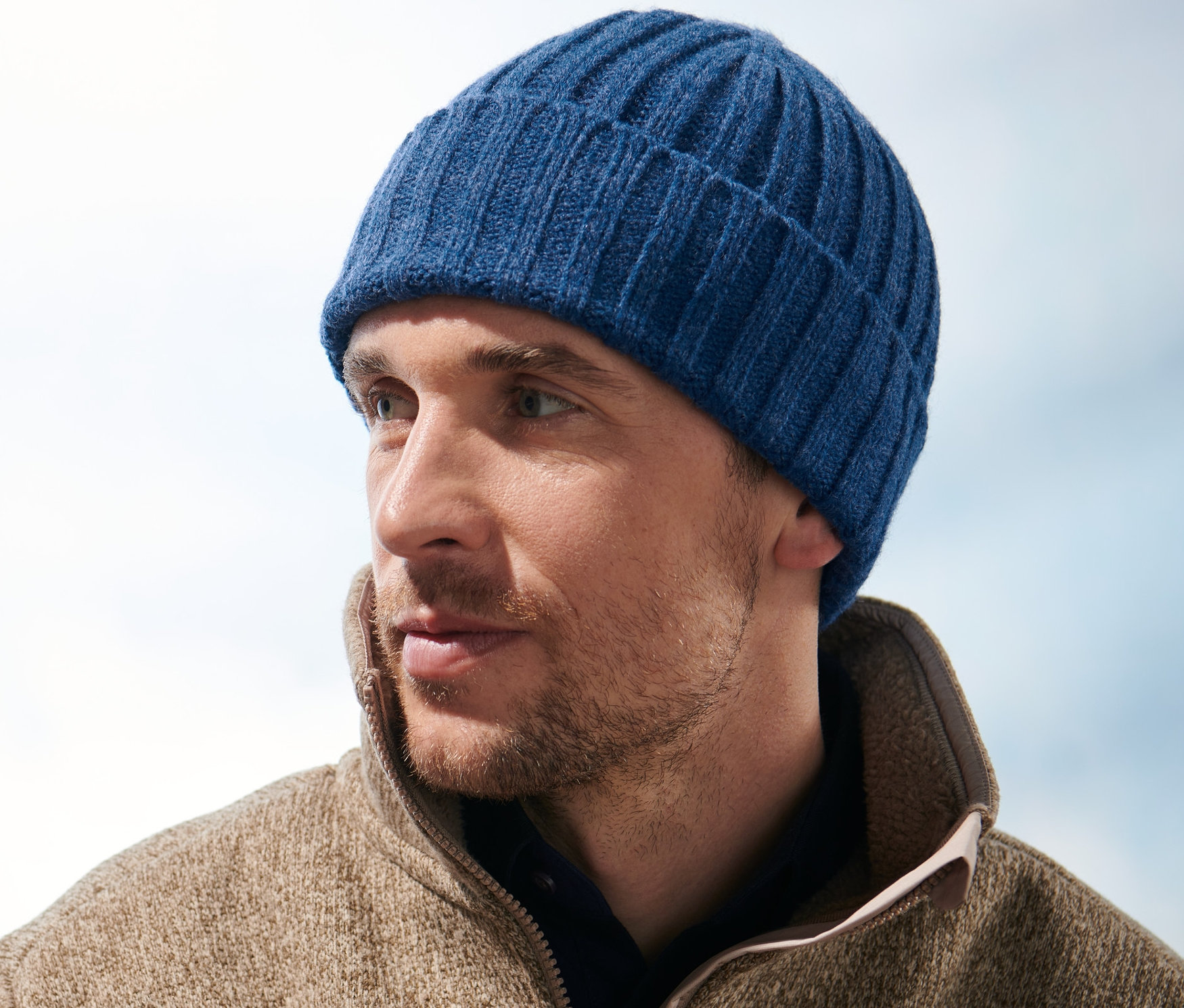 Mann mit Strickmütze blickt nach rechts.