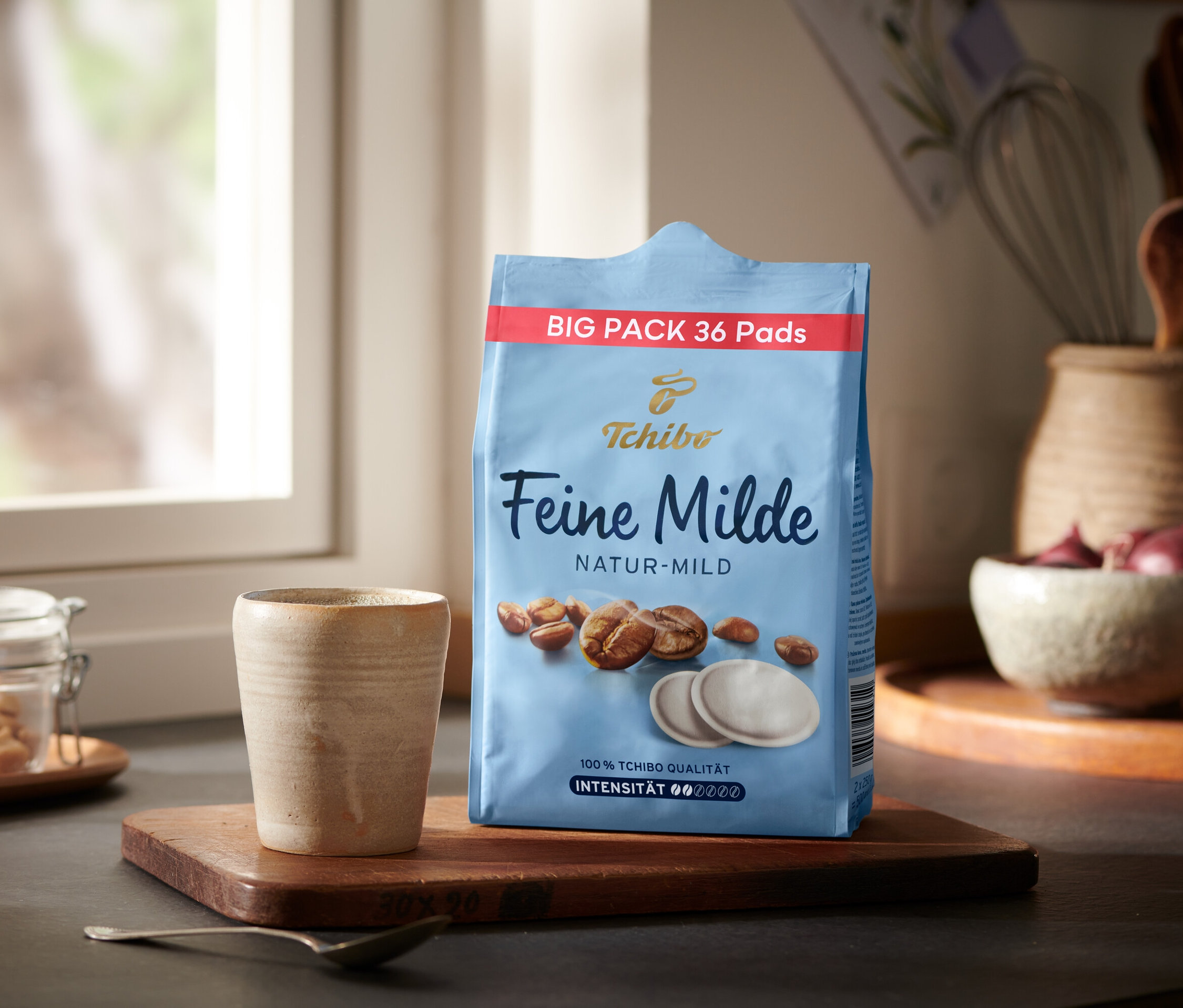 Eine Packung Feine Milde Pads - 36 Pads steht neben einer Tasse auf einem Holztablett.