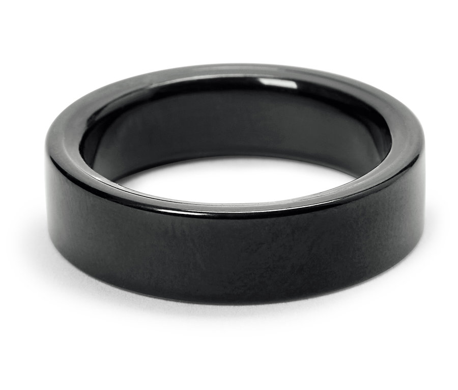 Detailaufnahme eines glänzenden, schwarzen Rings auf weißem Hintergrund.