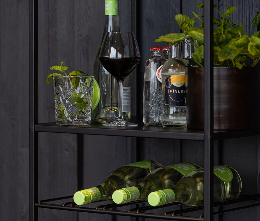 Schwarzes Woood Regal »Reese« aus Metall mit Getränken und Pflanze.