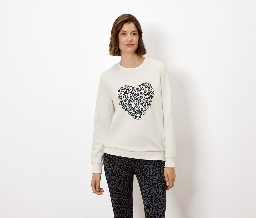 Frau trägt ein weißes Sweatshirt mit einem Tierdruckherz und Leggings mit Tierdruck.