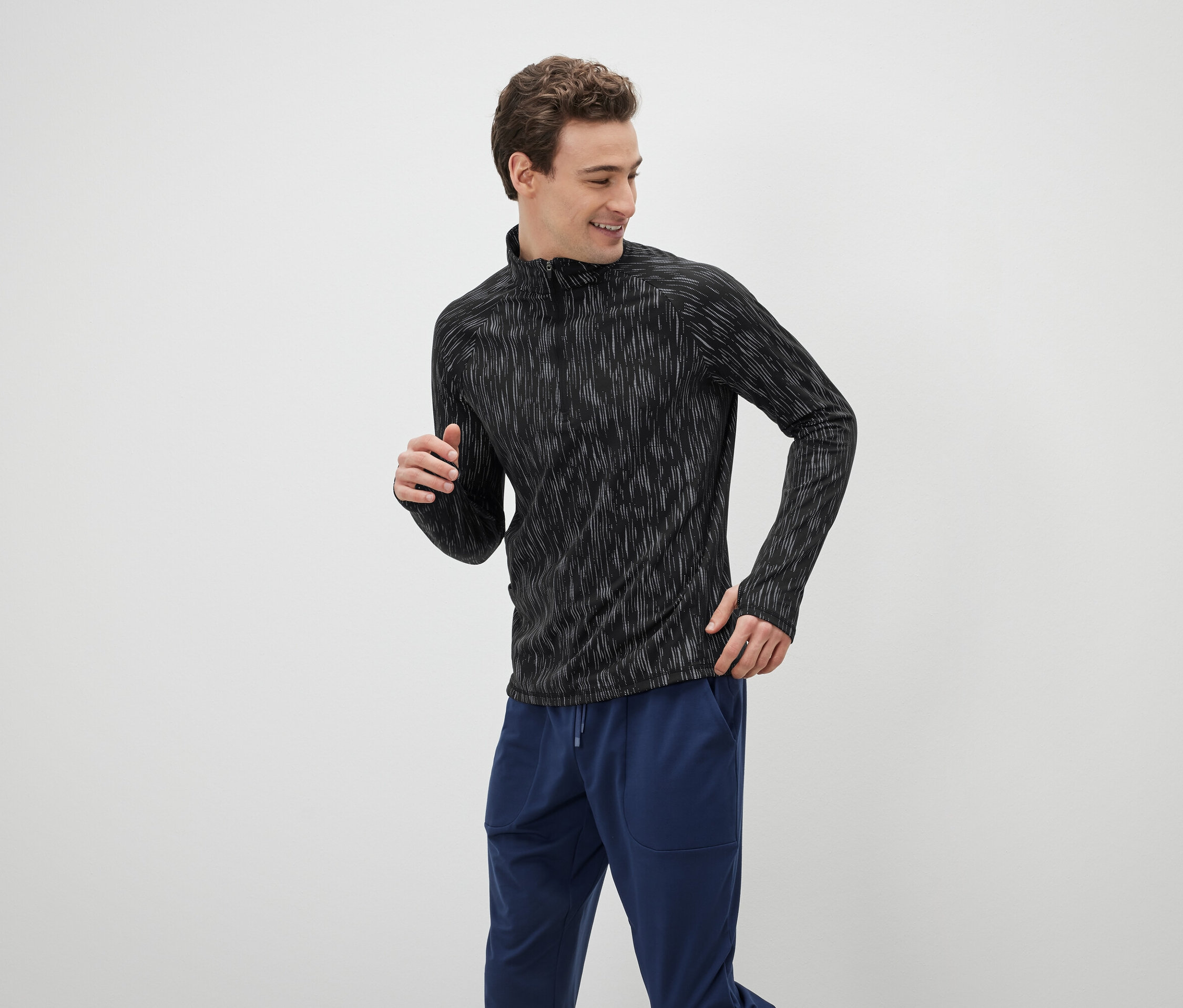 Mann in einem schwarzen, langärmeligen Sportoberteil und blauen Trainingshosen.