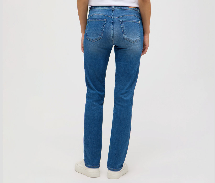 Rückansicht einer Frau, die Angels Jeans »Cici Push-Up«, Slim Fit und weiße Turnschuhe trägt.