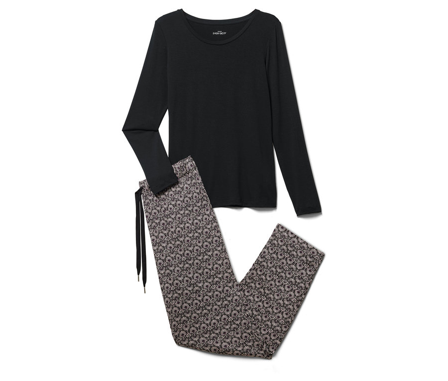 Ein schwarzes Schlafanzugoberteil mit langen Ärmeln und eine geblümte Schlafanzughose liegen auf einem weißen Hintergrund.