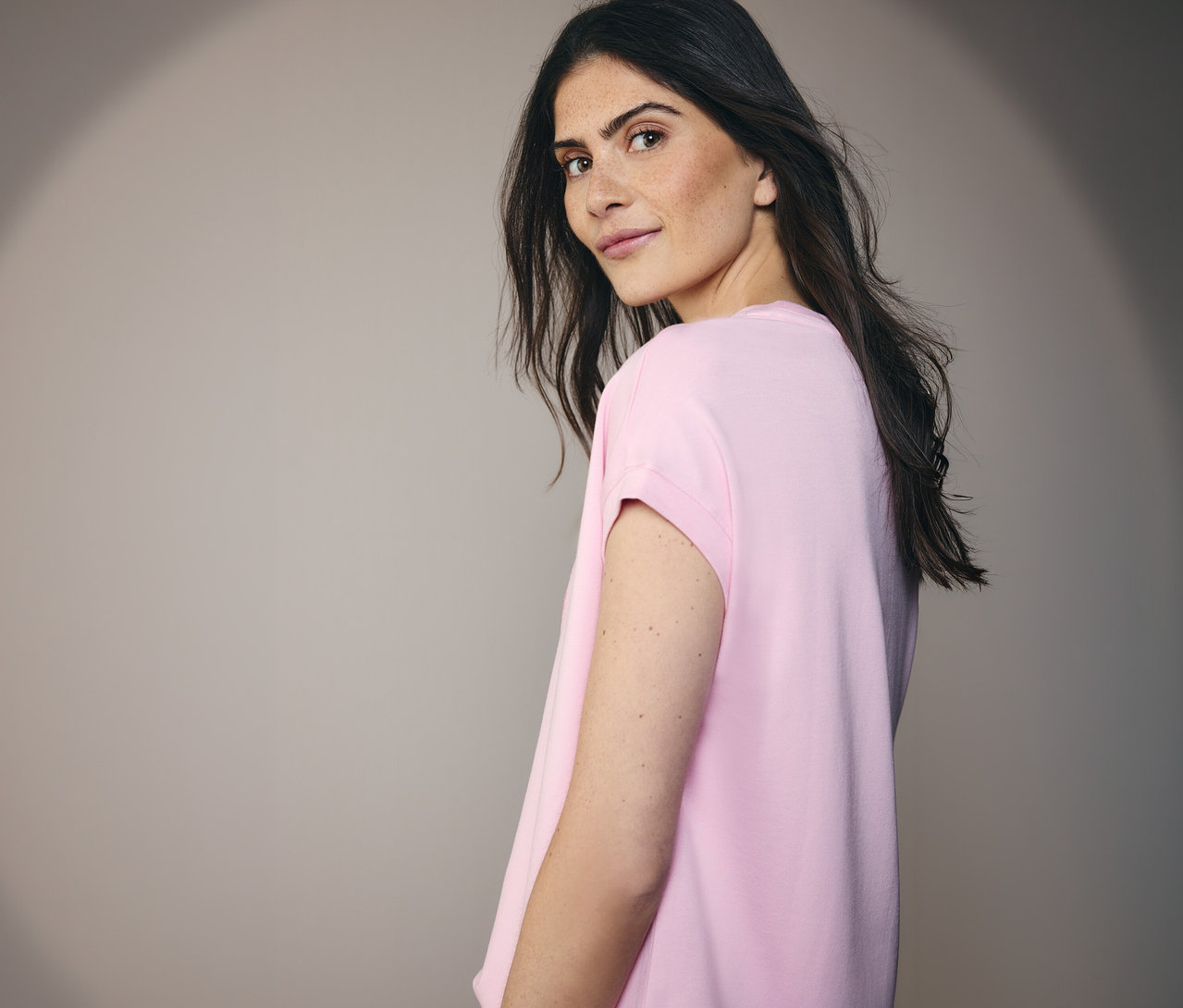 Frau, die ein CECIL Placement-Shirt trägt und über die Schulter blickt.