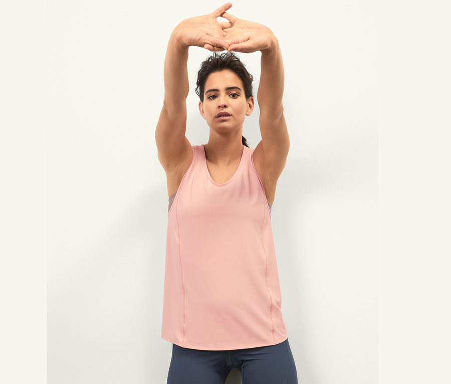 Frau mit Händen über dem Kopf trägt ein Sporttop.