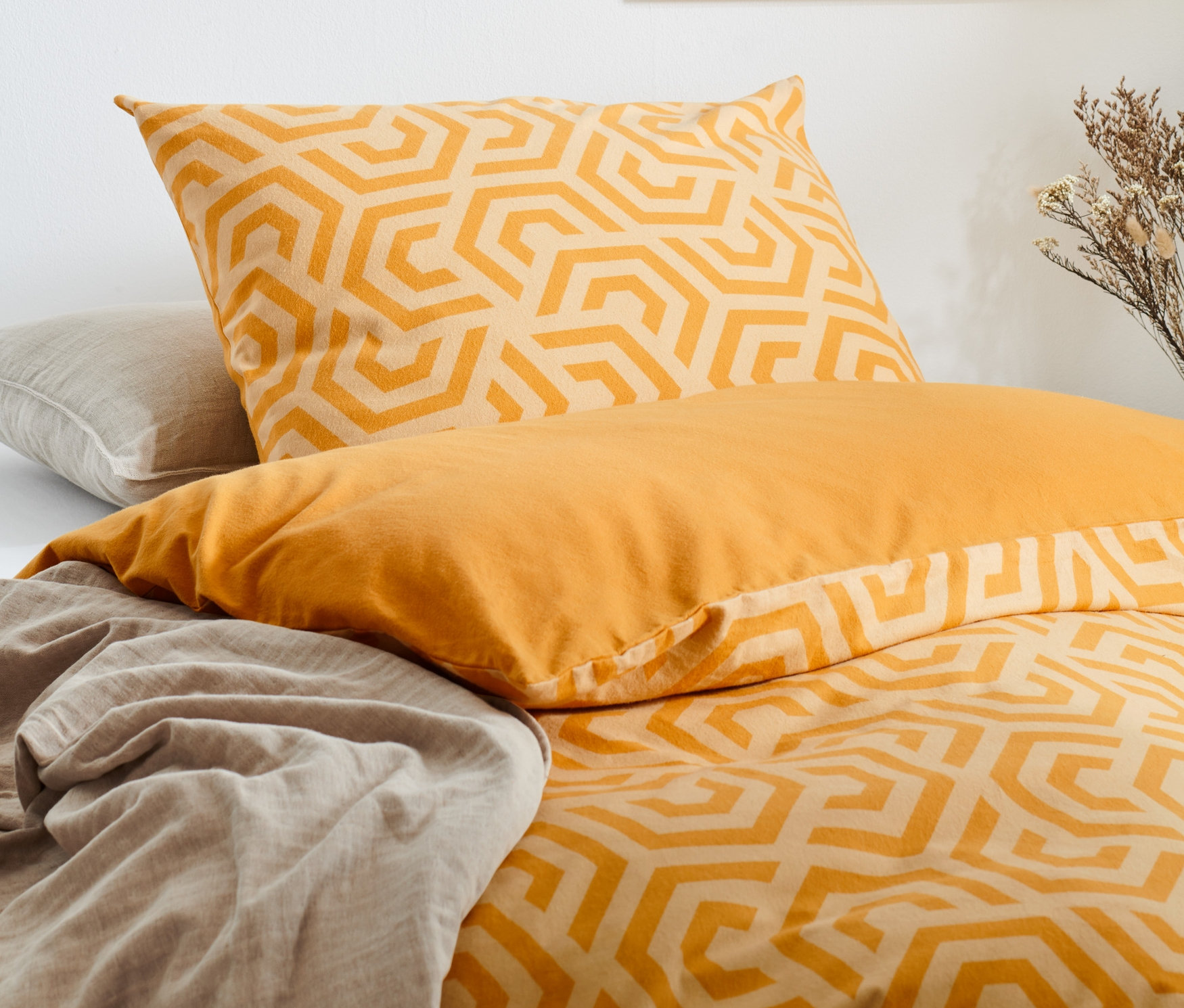 Gelbe Bettwäsche mit geometrischem Muster und ein Bettlaken.