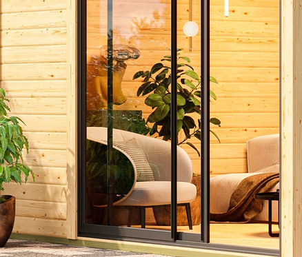 Außenansicht des Karibu Saunahauses „Gwen“ mit gläserner Schiebetür.