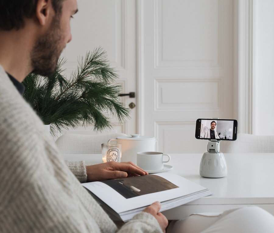 Mann sitzt am Tisch, liest ein Buch und nutzt eine Handyhalterung mit Bewegungssensor.