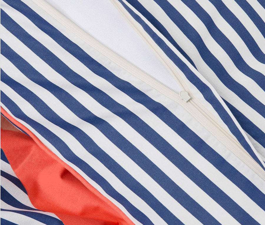 Detailansicht von Perkal-Bettwäsche mit Reißverschluss. Blau-weiße Streifen und orangefarbener Stoff.