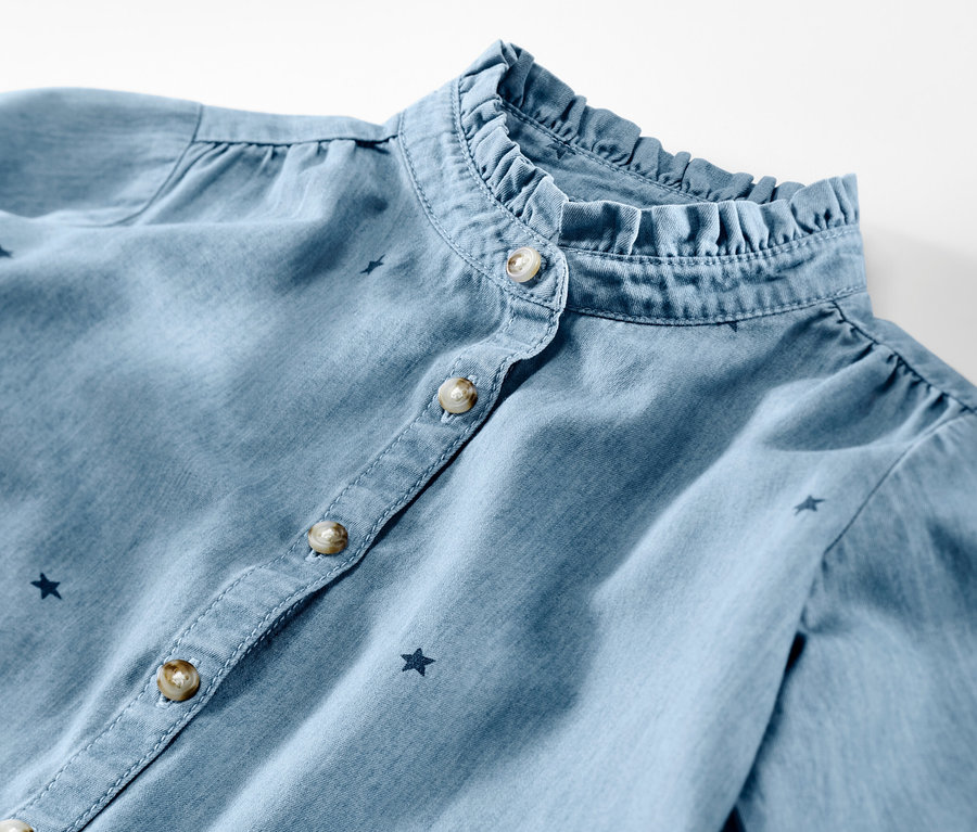 Detailansicht einer Kinder-Chambray-Bluse mit Rüschenkragen und Sternchen.