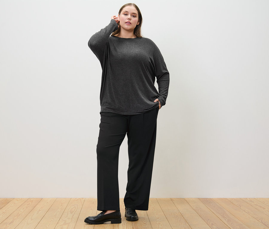 Frau posiert in Komfort-Jerseyhose und Fledermausshirt.