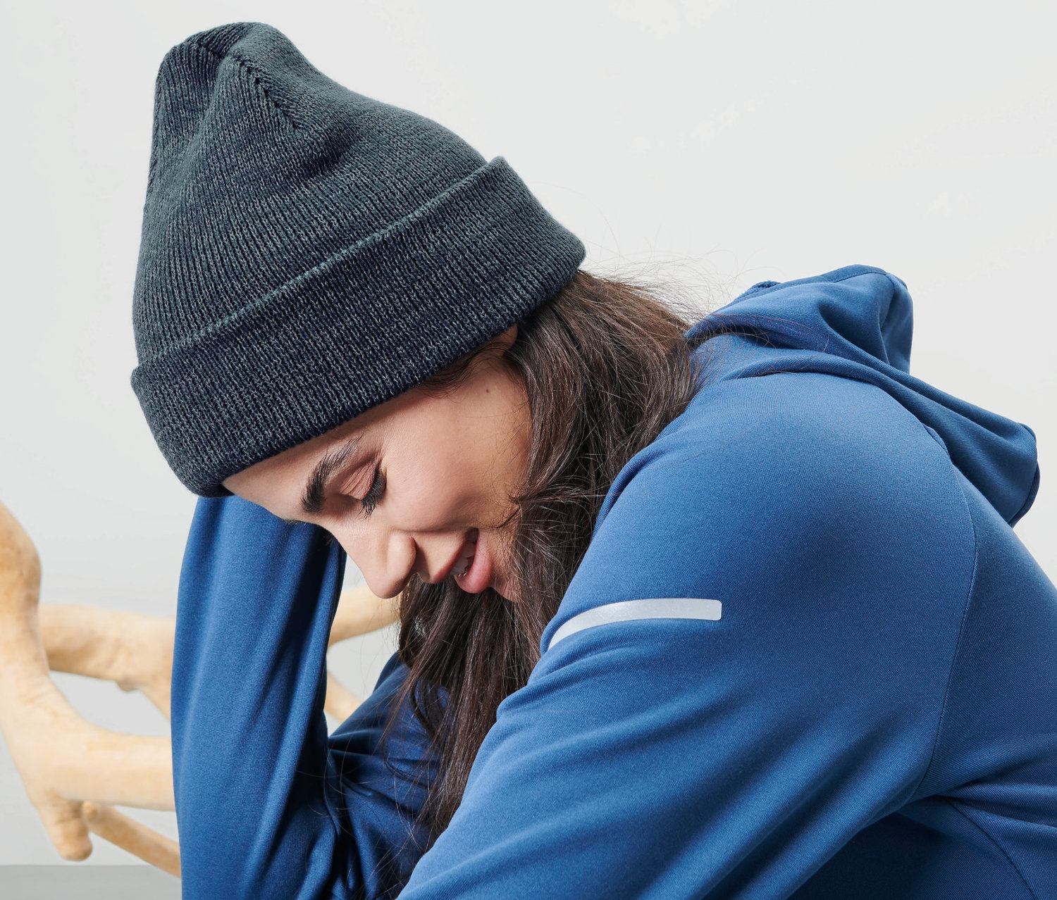 Frau sitzt und trägt eine blaue Strickmütze.