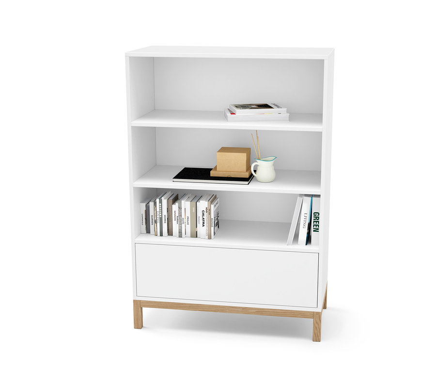 Weisse Kommode mit Schublade und Regalen, auf denen Bücher und Dekorationen stehen.