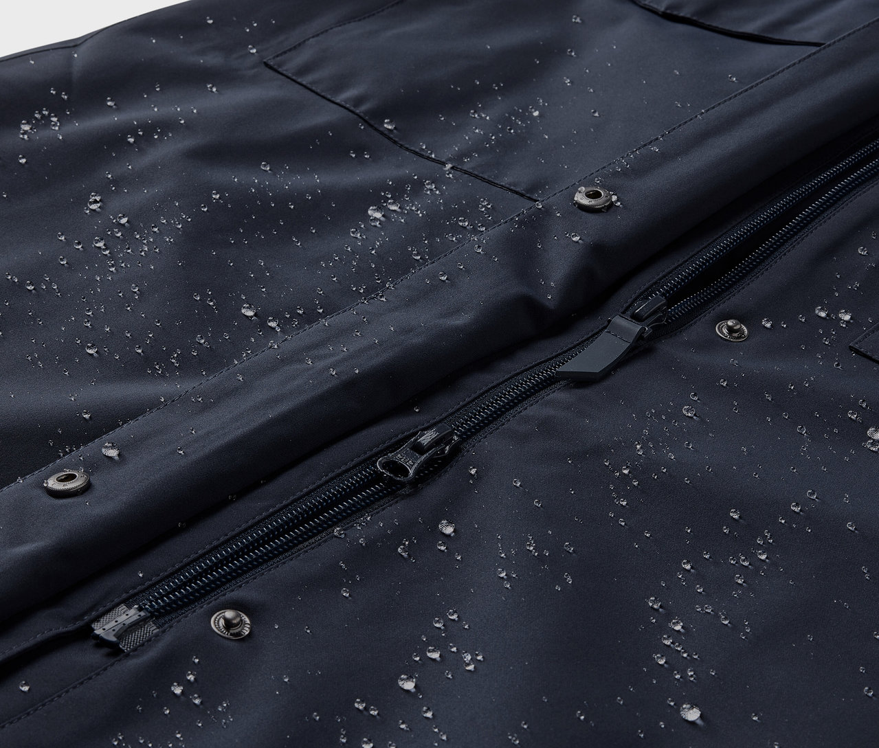 Nahaufnahme eines Regentrenchcoats mit Wassertropfen.