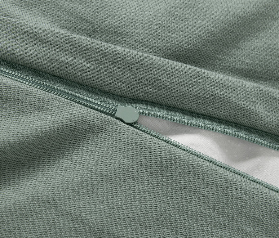 Detailaufnahme eines grünen Bettbezugs mit Reißverschluss.