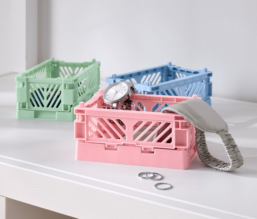 Drei farbige Faltboxen auf einem Tisch, eine rosa mit einer Uhr, eine blaue und eine grüne.