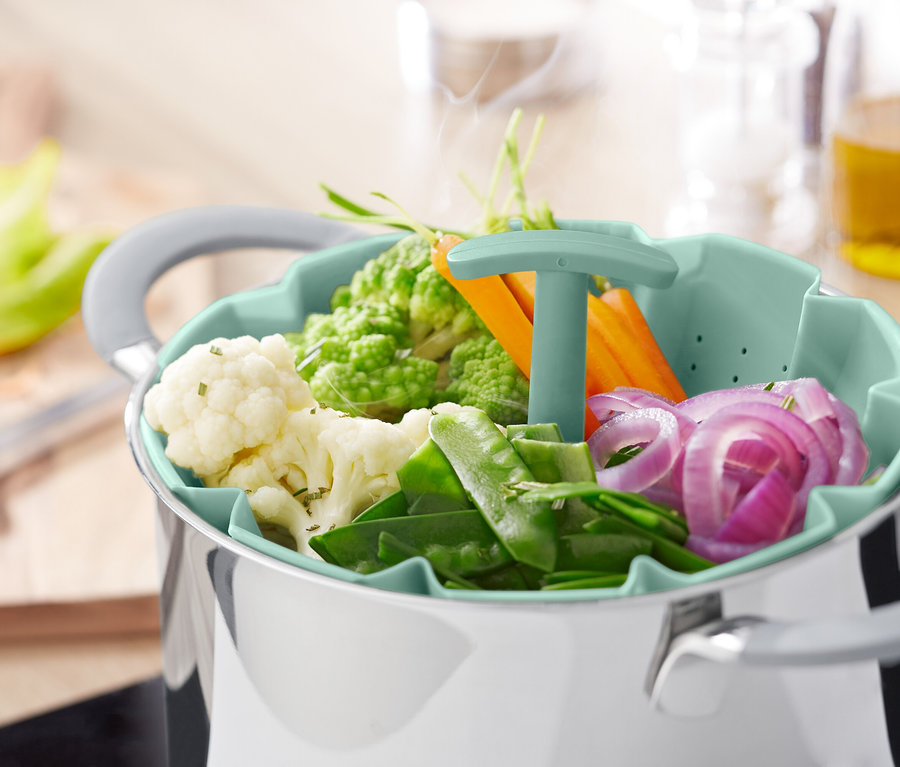 Gemüse in einem Dämpfsieb über einem Topf.