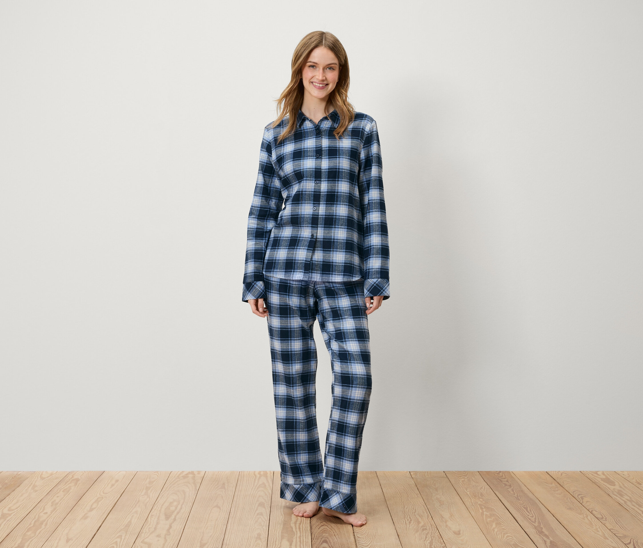 Eine Frau steht und trägt einen blau karierten Pyjama.