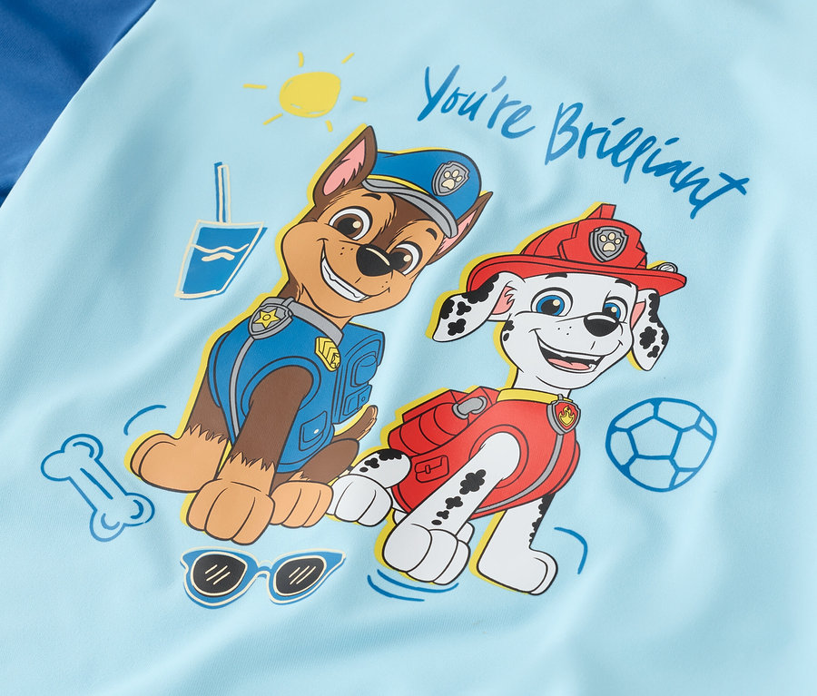 Auf hellblauem Stoff sind Chase in Polizeiuniform und Marshall in Feuerwehruniform abgebildet.