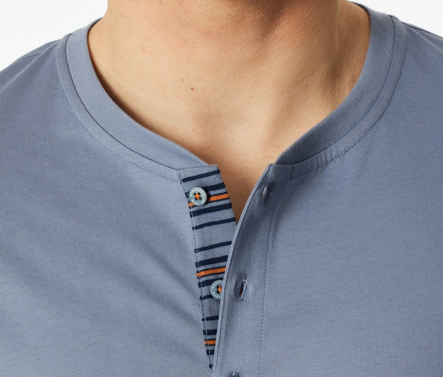 Nahaufnahme eines Mannes, der ein blaues Poloshirt mit Knöpfen und gestreiftem Detail trägt.