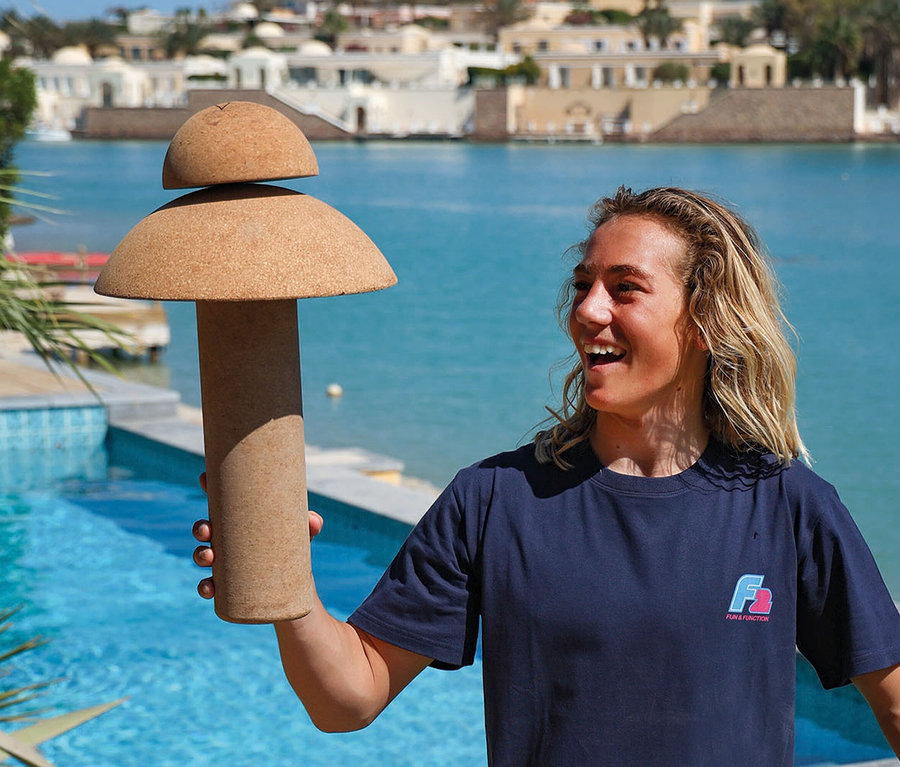 Frau hält ein F2 Balance Board Set Pill mit Korkrolle vor einem Pool.