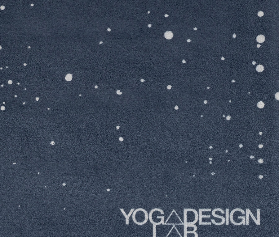Nahaufnahme einer dunkelblauen Yogamatte mit weißen Punkten und dem Yoga Design Lab Logo.