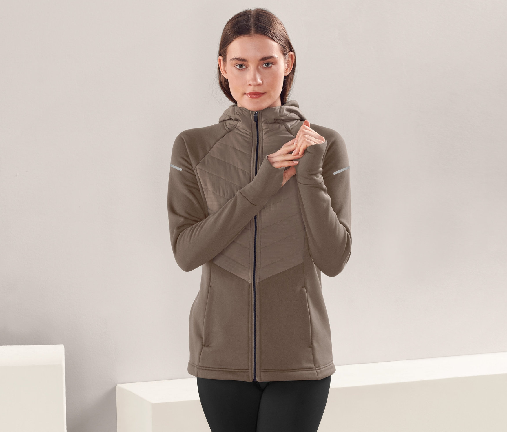 Frau trägt eine braune Thermojacke mit Kapuze.