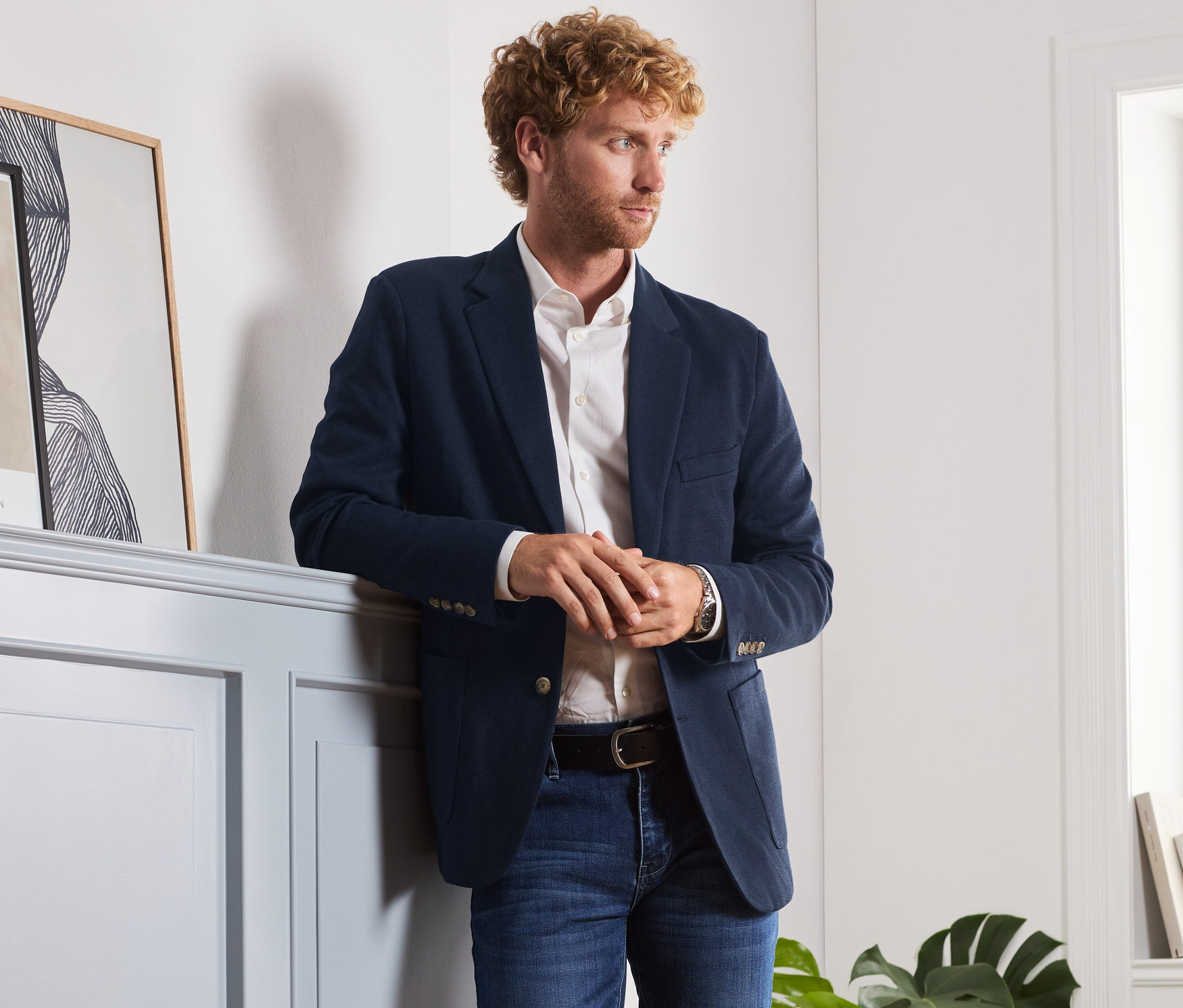 Mann an Wand gelehnt trägt ein Sakko.