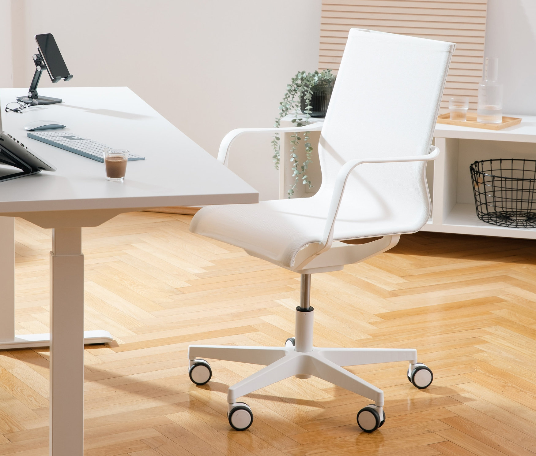 Weißer Schreibtisch mit Laptop, Telefon und Glas neben weißem Topstar Bürostuhl »SITNESS Life 40«.