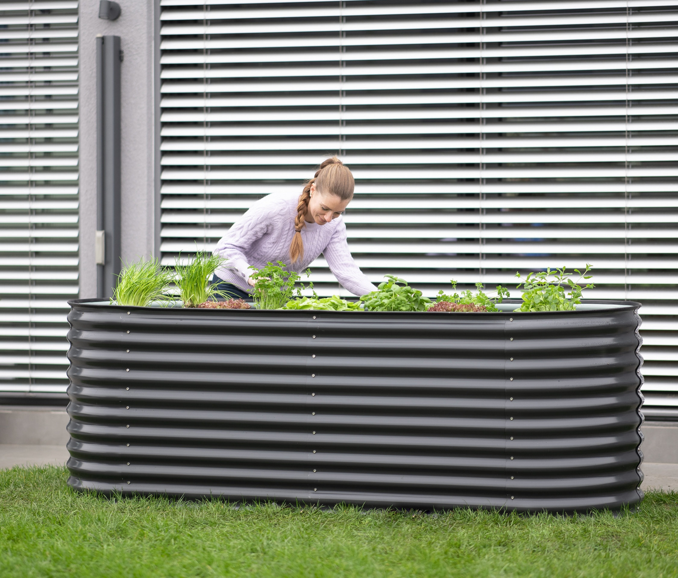 Frau arbeitet in einem ovalen Hochbeet, Breite ca. 240 cm.