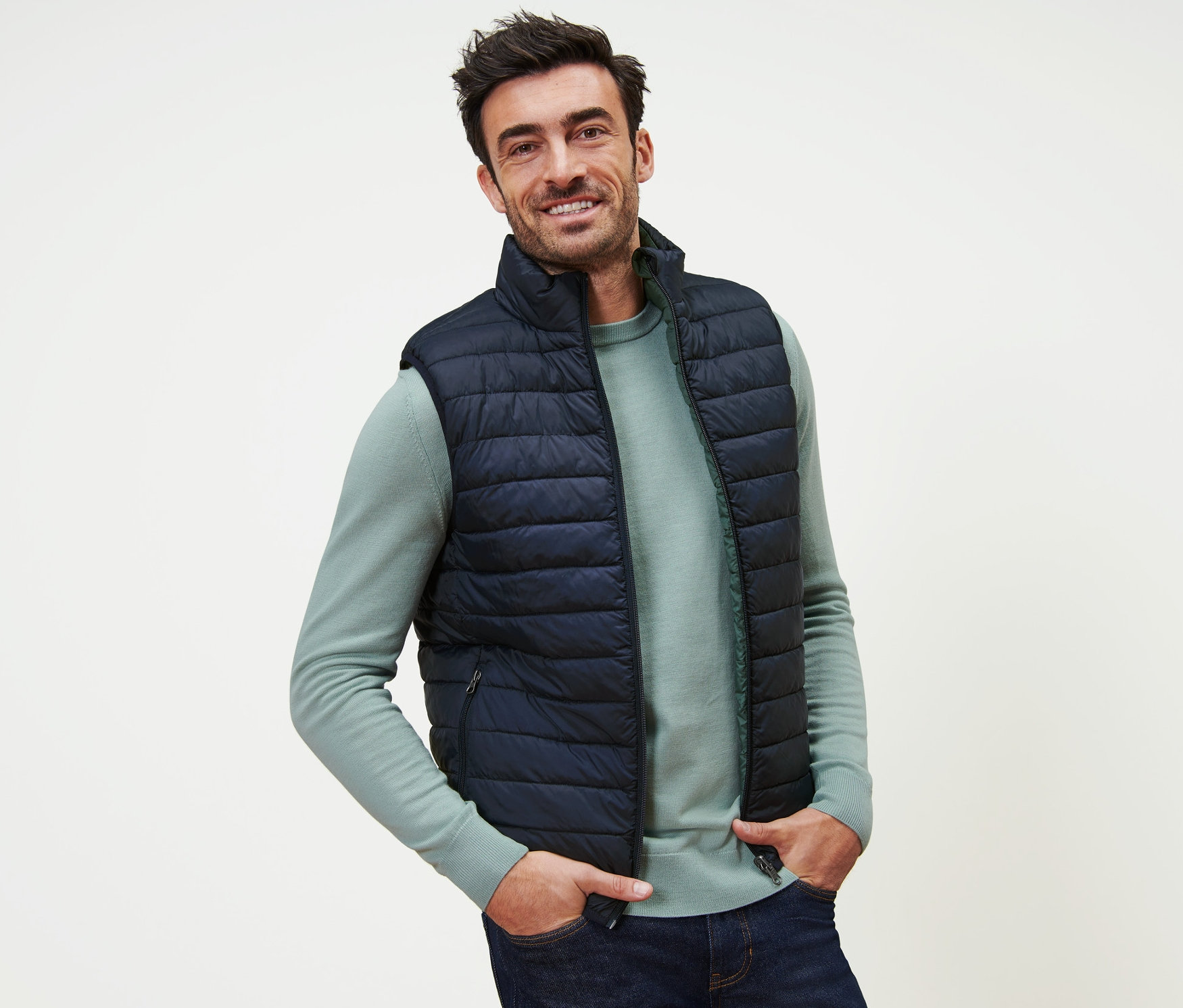 Mann lächelt und posiert in dunkelblauer Wendeweste.