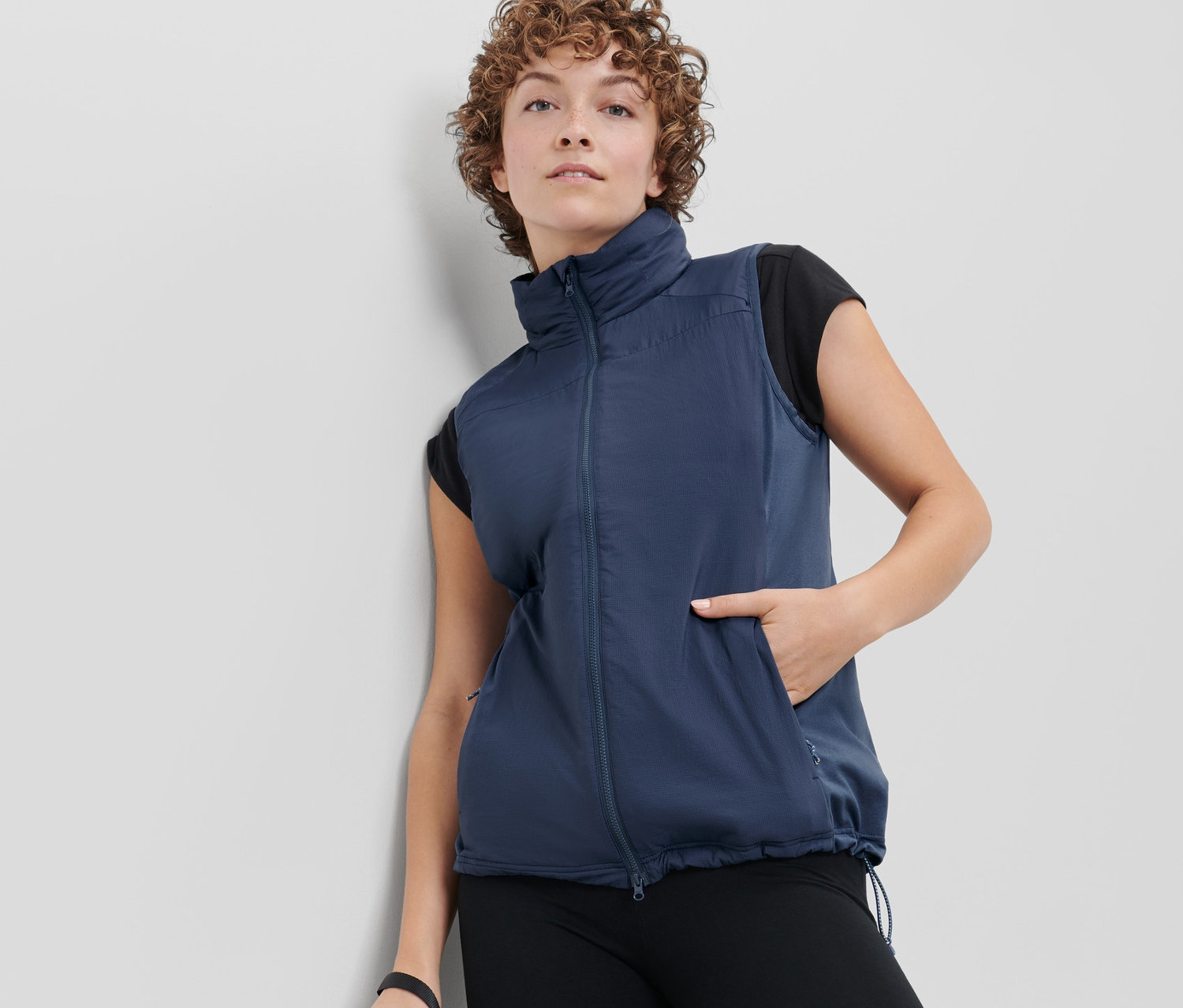 Frau trägt eine Hybrid-Weste »pack light« und hält eine Wasserflasche.