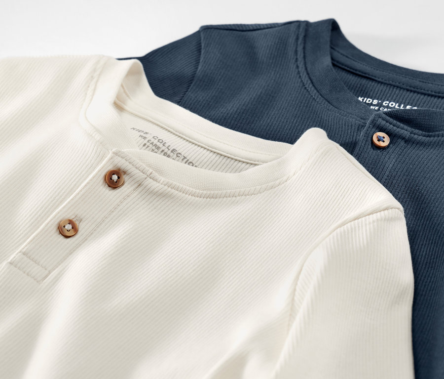 Zwei Kinder-Henley-Shirts mit Rippstruktur liegen übereinander.