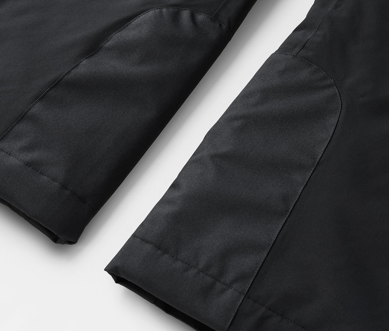 Detailaufnahme von schwarzen Hosenbeinen mit kontrastierenden Einsätzen.