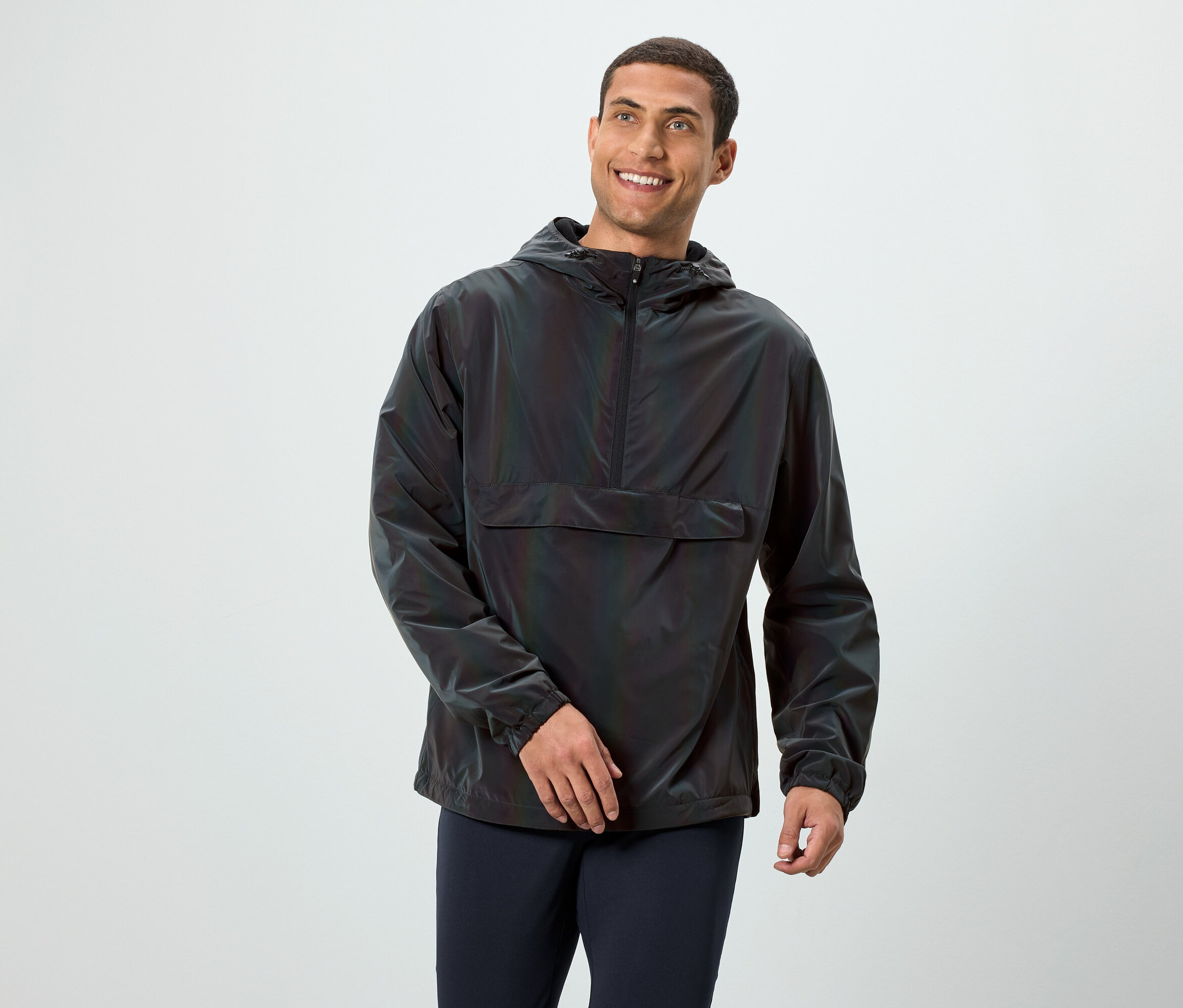 Ein lächelnder Mann posiert in einer dunklen, langärmligen Kapuzenjacke.