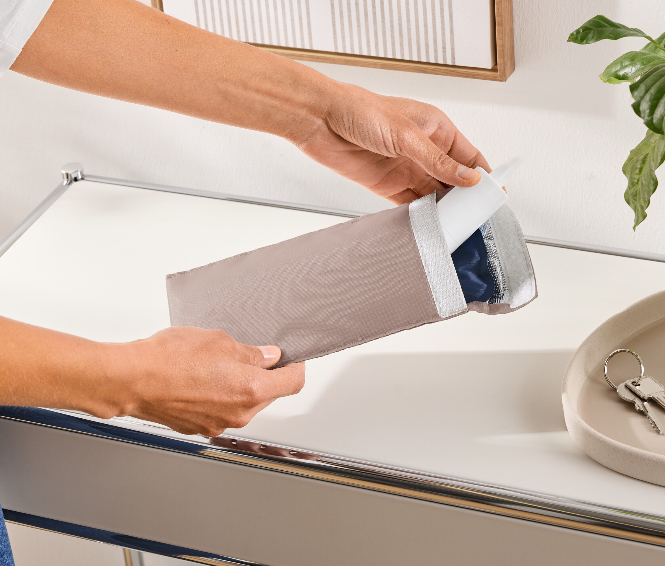 Eine Person öffnet eine längliche, beige Schutzhülle, die ein blaues Produkt enthält.