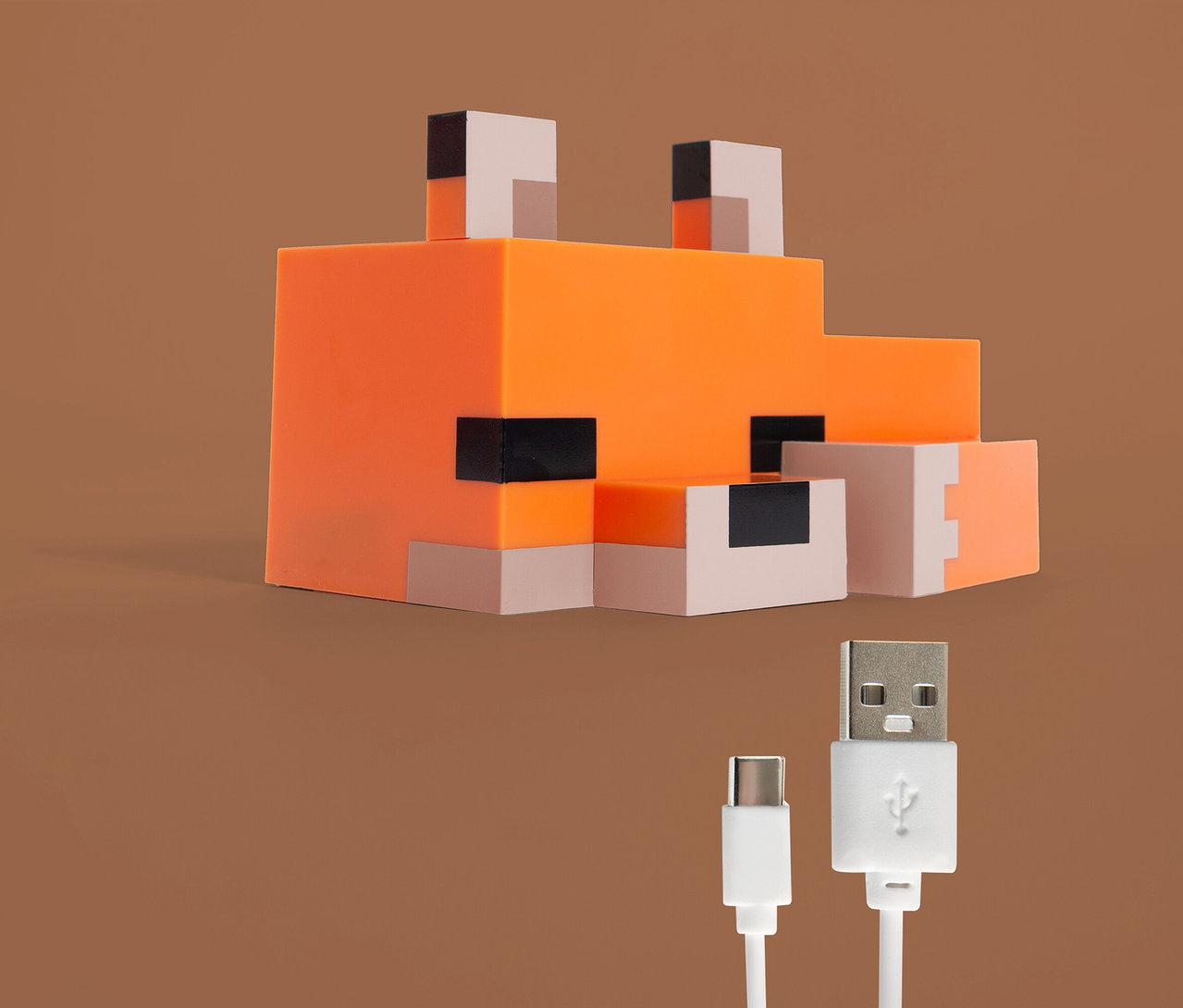 Ein orangefarbener, blockförmiger Fuchs, darunter ein USB-Kabel vor einem braunen Hintergrund.