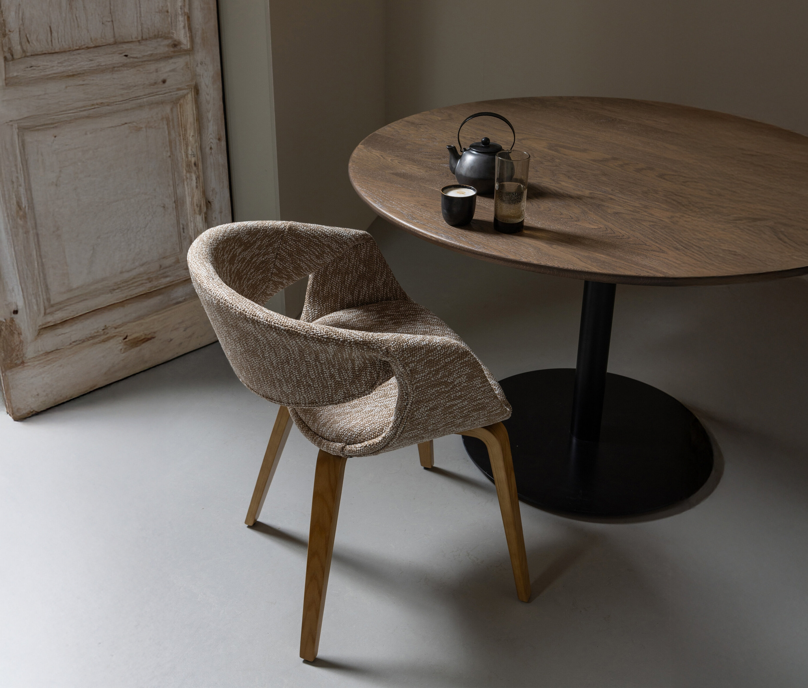 Ein sandfarbener WOOOD Esszimmerstuhl »Yossi« mit naturfarbenem Holzfuß aus einem 2er-Set steht neben einem Holztisch mit Teekanne und Gläsern.