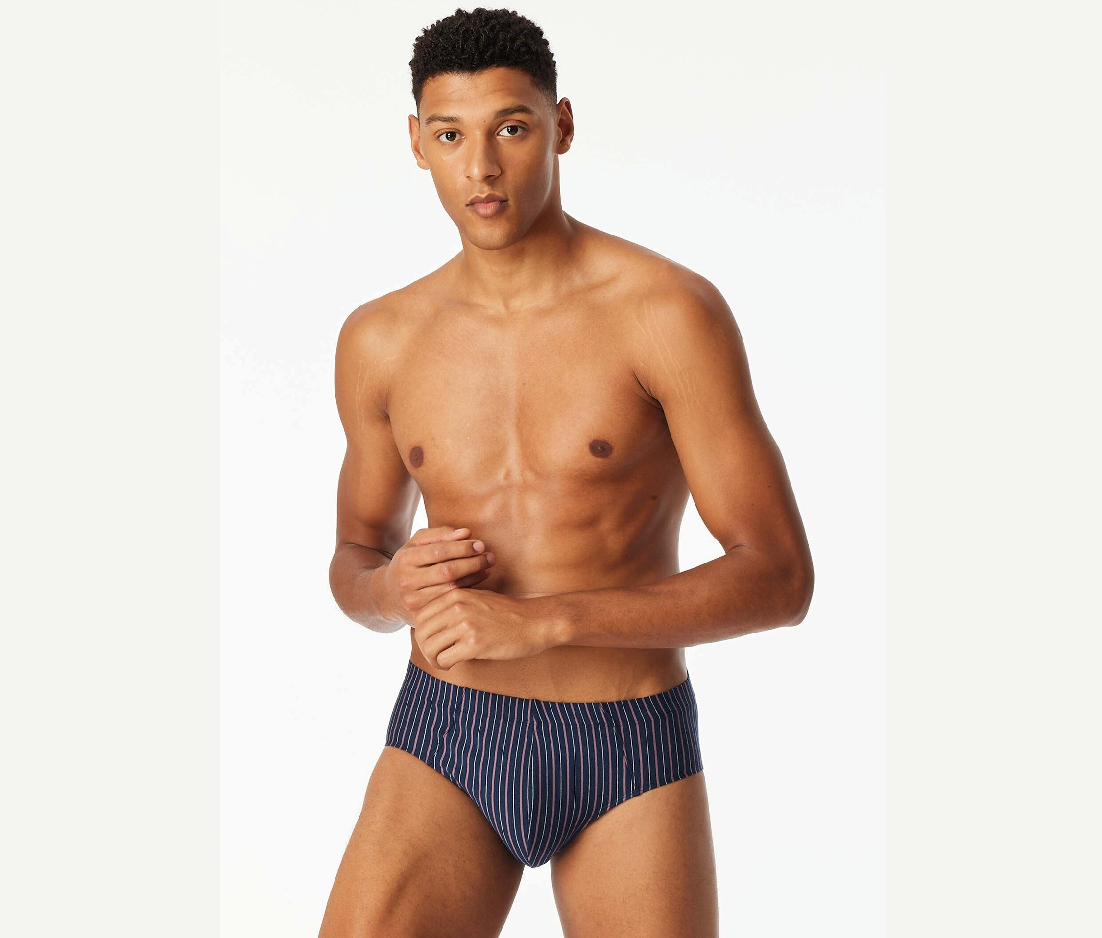 Mann mit freiem Oberkörper posiert in blauen Slips mit Streifen.