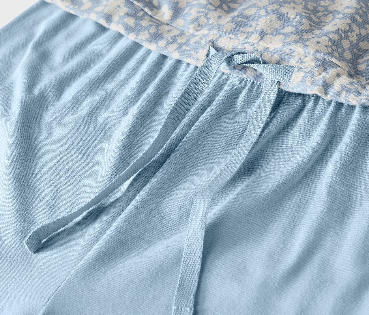 Detail einer hellblauen Pyjamahose mit Blumenoberteil und Kordelzug.