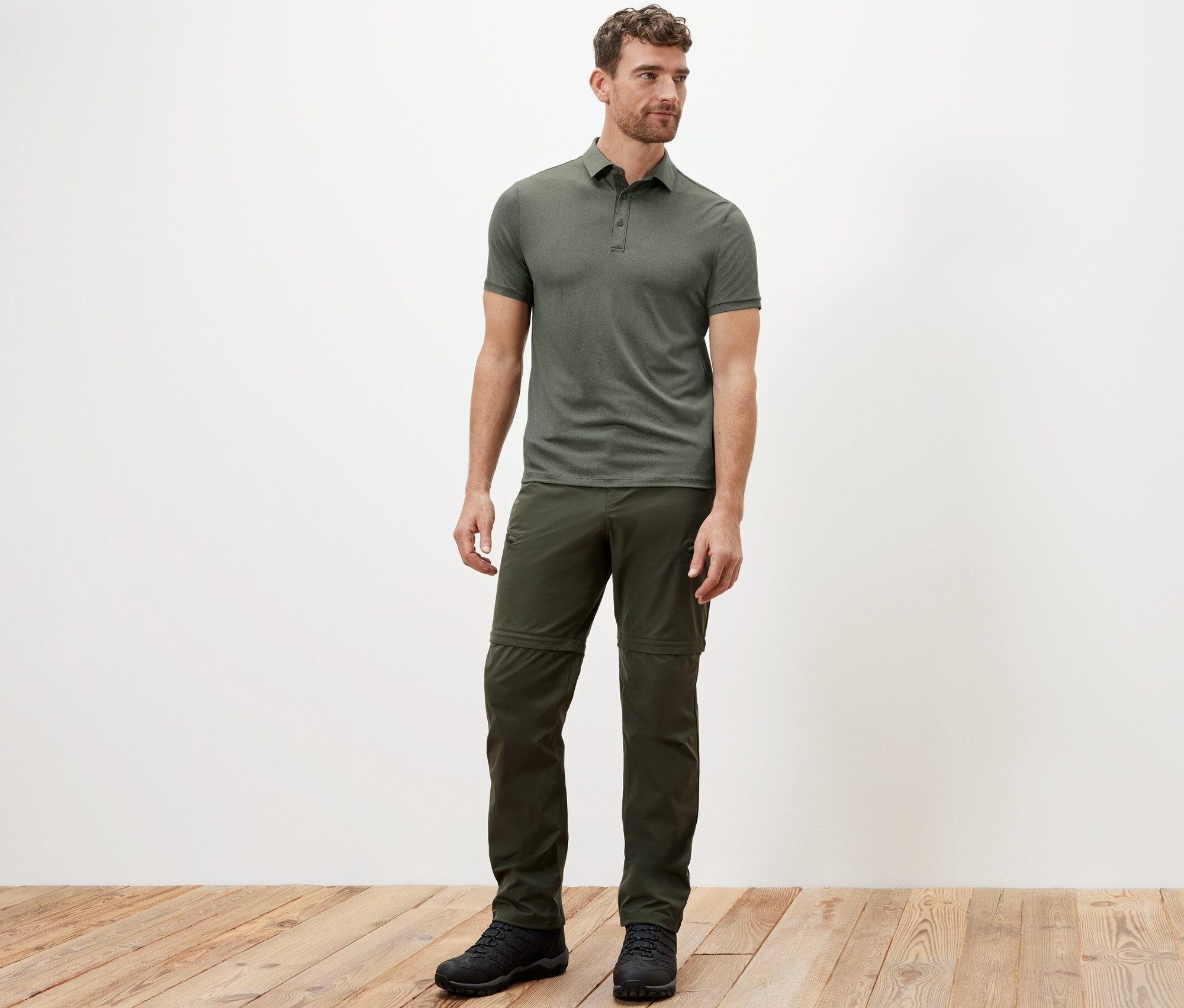 Mann steht und trägt ein khaki Funktions-Poloshirt.