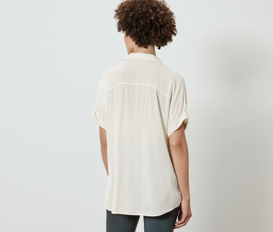 Rückansicht einer Frau in cremeweißer Bluse.