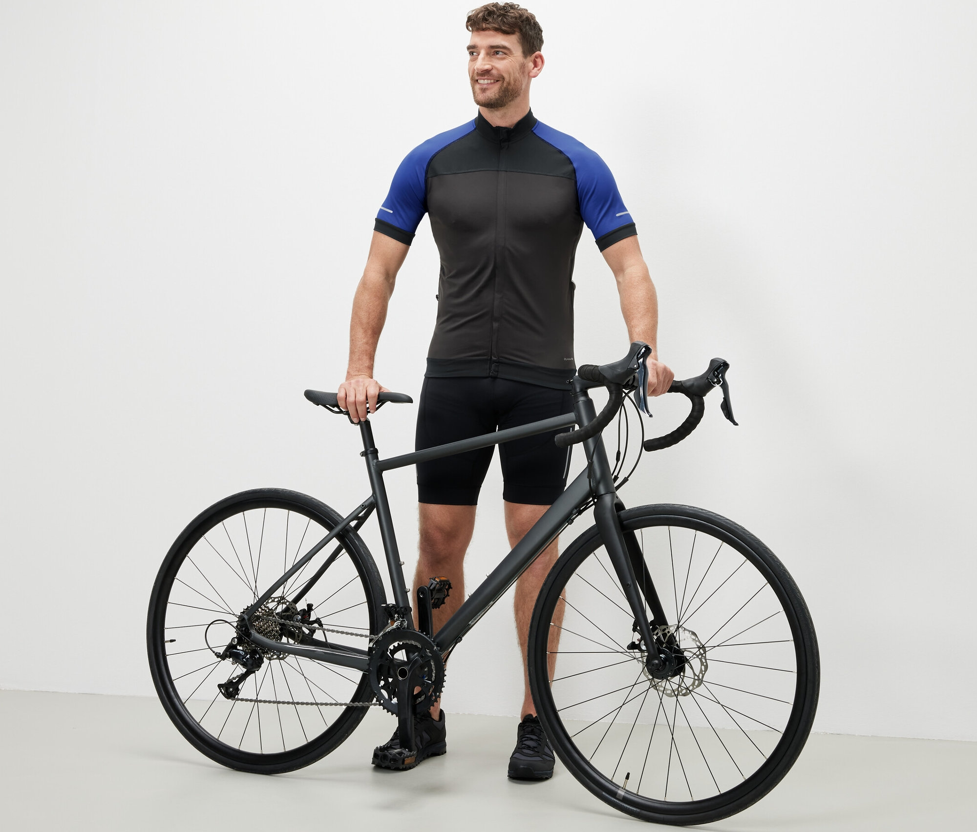 Mann steht neben einem Fahrrad und trägt ein blaues Fahrrad-Trikot.