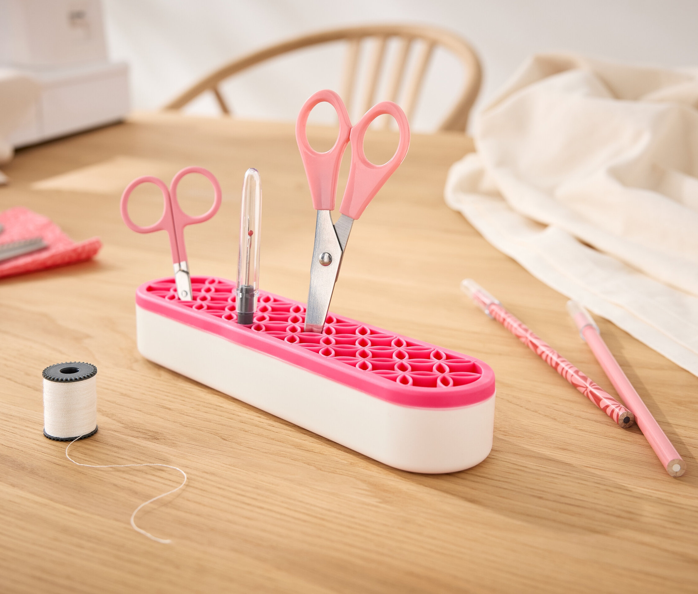 Schere und Stift befinden sich in einem Mehrzweck-Organizer auf einem Holztisch.