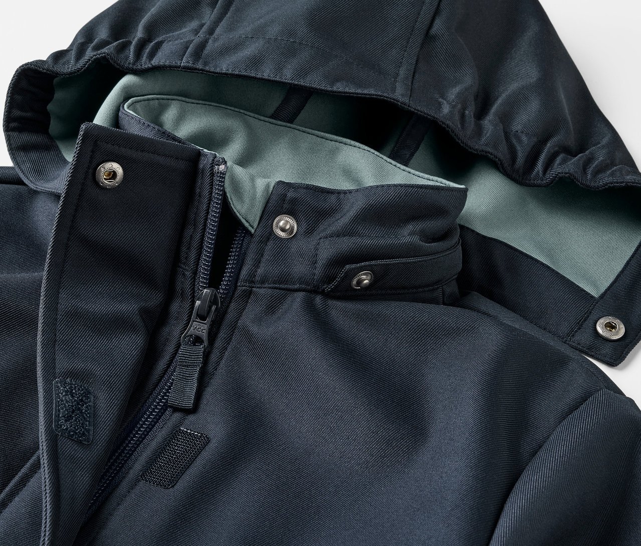 Detailansicht eines Kinder-Softshellmantels mit Kapuze und Reißverschluss.