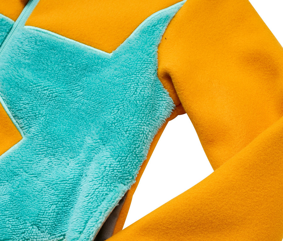 Detail einer gelb-türkisen Jacke mit Tasche.